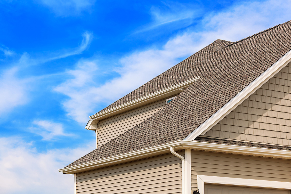 Side view of brown asphalt roof on a beige home