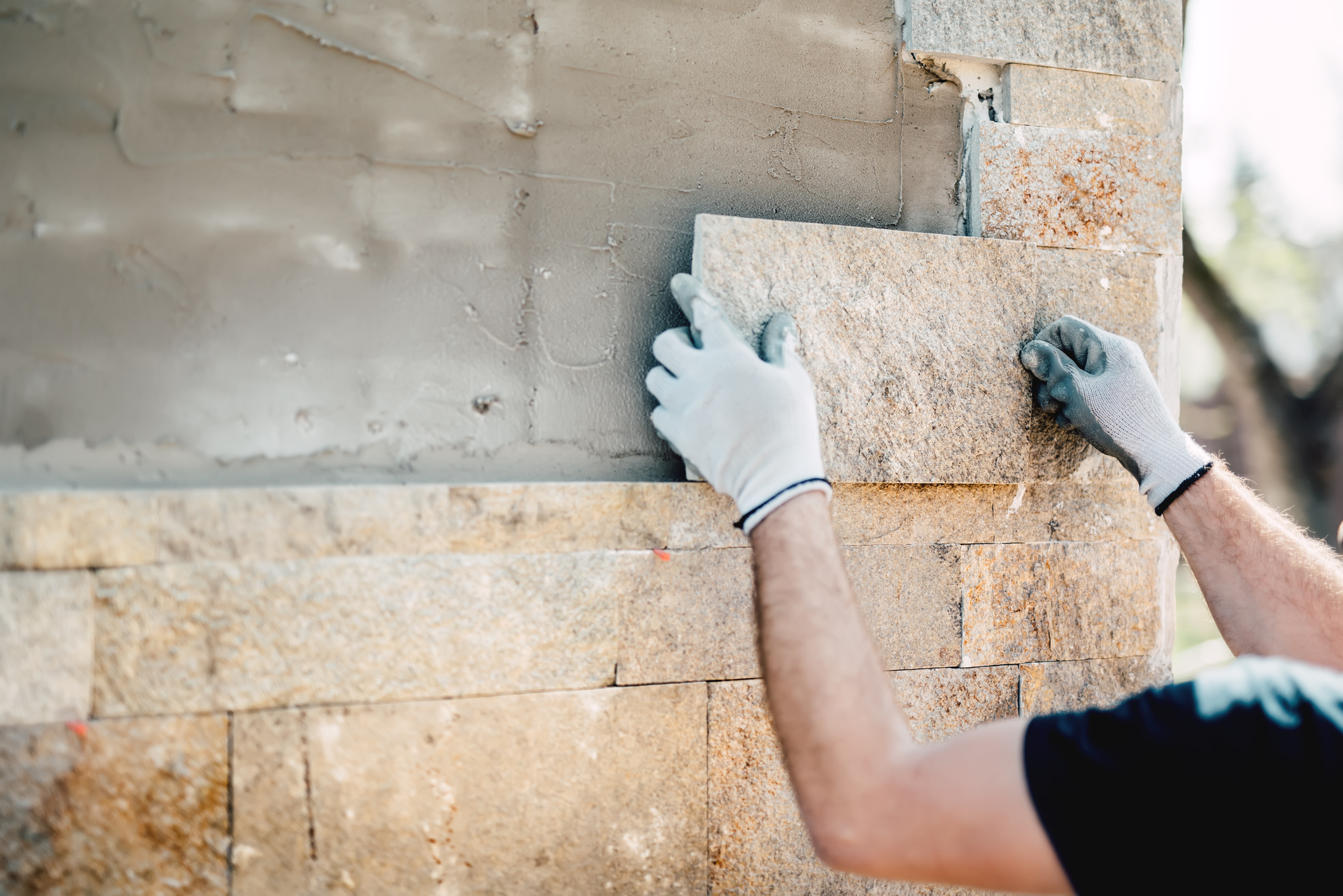 Construction worker installing stone on facade